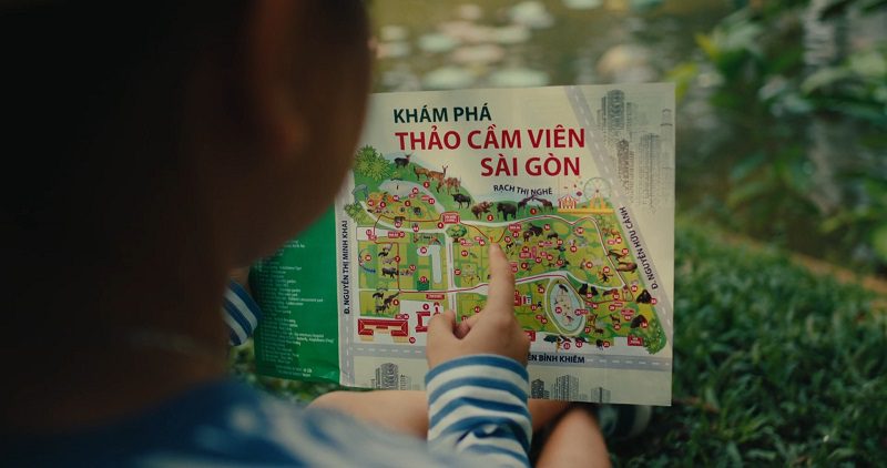 Child pointing at a colorful map of Saigon Zoo, exploring travel destinations.