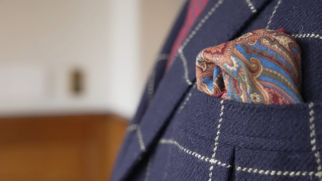 Patterned pocket square tucked into a blue checked suit jacket